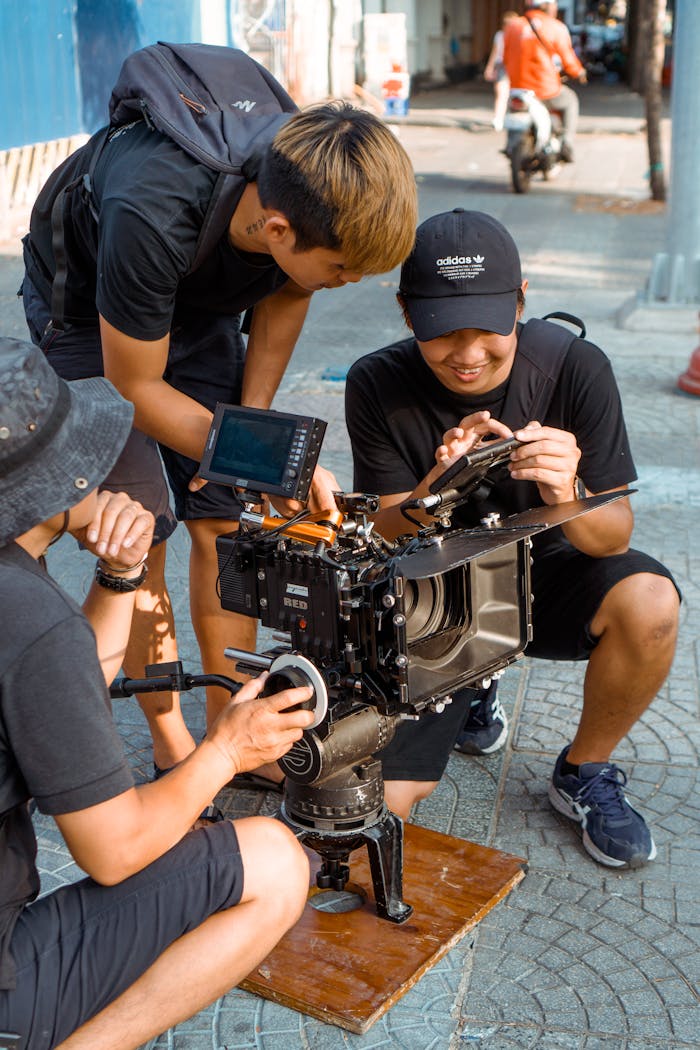 Filmmakers adjusting camera equipment on set outdoors, showcasing collaborative effort.